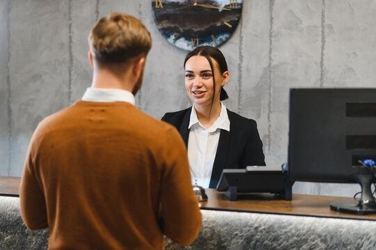 Medewerker achter hotelbalie spreekt met een gast over zijn verblijf